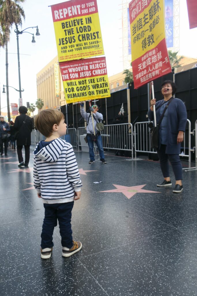 Enfant sur Hollywood Boulevard devant des manifestants Belive in the lord.