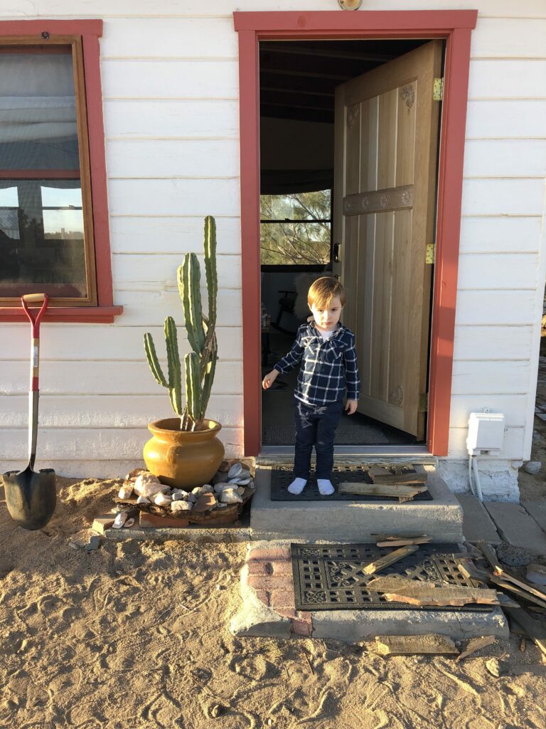 Enfant dans embrasure de la porte d'une maison dans le désert