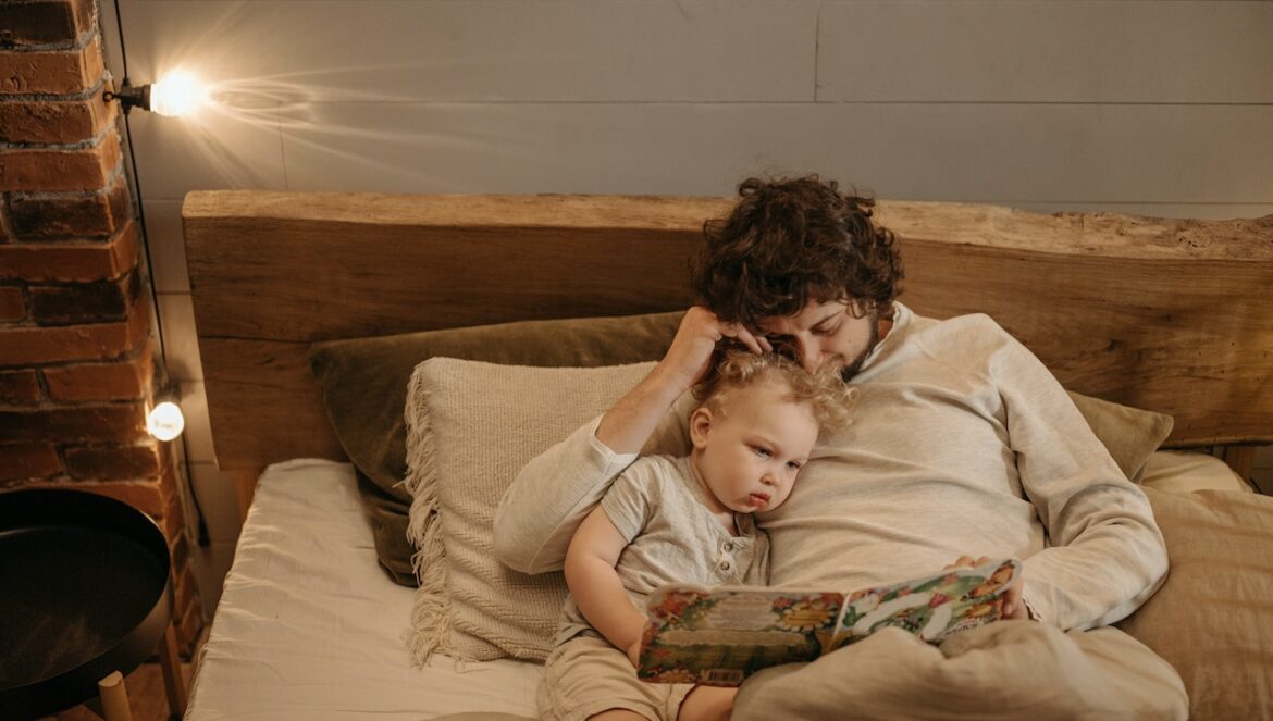 Un papa lit une histoire à son enfant dans le lit