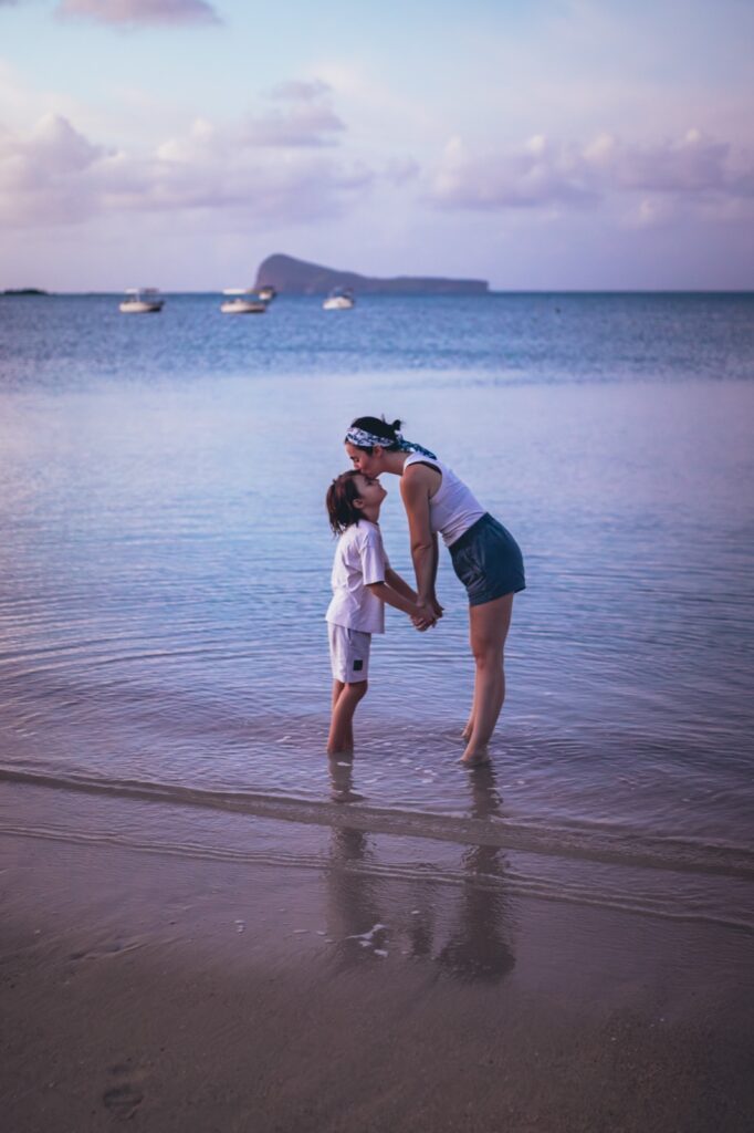 maman embrassant son enfant sur une plage de l'île Maurice au coucher du soleil